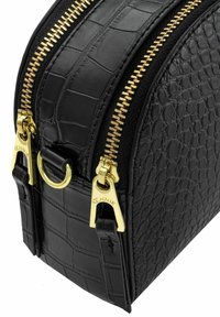 Czarna torba z teksturowanej skóry, z dwoma złotymi zamkami błyskawicznymi i uchwytami, z motywami krokodylej skóry oraz groszku.