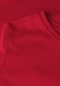 Roter Baumwollstoff mit einer glatten, gerippten Textur. Verfügt über einen Rundhalsausschnitt und einen leichten Stretch. Keine zusätzlichen Muster oder Verzierungen sichtbar.