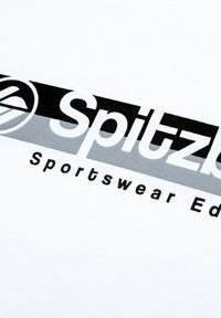 Weißer Stoff mit einem schwarzen und grauen Logo "Spitz" sowie den Worten "Sportswear Ed." Das Design hat eine glatte Textur und fett gedruckte Schriftzüge.