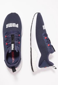 Námořnické sportovní boty z prodyšné síťoviny s bílou podrážkou. Mezi vlastnosti patří polstrovaný límec, červené akcenty a výrazné bílé logo "PUMA" na svrchní části.