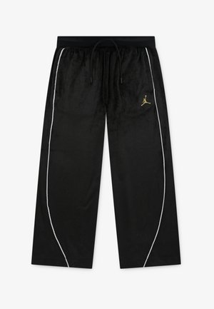 Calças de veludo preto com um cós elástico preto, com detalhes brancos nas laterais e um logo Jumpman dourado na coxa esquerda.