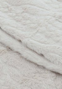 Tessuto di pelliccia sintetica grigio chiaro morbido e piegato con una texture soffice e vaporosa mostrata in un primo piano.