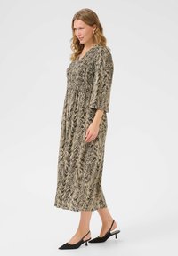 Maxiklänning i ett svart och beige virvlande mönster, med smockdetaljer, trekvartslånga ärmar och avslappnad passform. Elegant knälång silhuett.