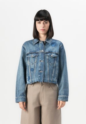 Kuttet blå denimjakke med knapper foran, to brystlommer og broderte detaljer. Har klassisk krage og frynset kant.