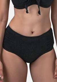 Parte inferiore di bikini nera a vita alta con un sottile motivo testurizzato, caratterizzata da dettagli arricciati sui lati per una forma e un supporto aggiuntivi.