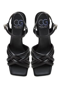 Sandales à talons hauts en cuir noir avec des brides entrecroisées, bout carré et fermeture à boucle à la cheville. Logo de la marque embossé sur la semelle intérieure.