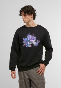 Sort sweatshirt med et farverigt grafisk print med teksten "JUST RHYSE" i hvid, der viser blå og lilla sprøjt.