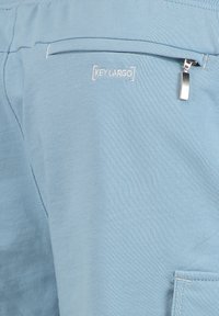 Jasnoniebieskie szorty wykonane z miękkiego, gładkiego materiału. Posiadają boczną kieszeń z suwakiem oraz haftowane logo marki.