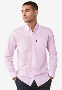 Lichtroze langemouw shirt met knoopsluiting en een borstzak, en knopen aan de voorkant. Gemaakt van een gladde katoenmix stof.
