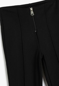 Schwarze hochtaillierte Hose mit einem Reißverschluss vorne und dekorativen Falten. Hergestellt aus einem strukturierten Stoff mit glatter Oberfläche.