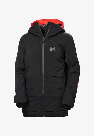 Chaqueta negra con capucha interior roja. Presenta un cierre frontal con cremallera, capucha ajustable y estampado de logo en el pecho. Tejido duradero y texturizado.