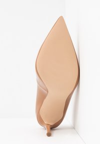 Chaussure à talons aiguilles couleur nude avec un bout pointu. Tige en cuir lisse avec une finition élégante, talon effilé et semelle texturée pour une meilleure adhérence.
