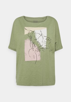 Oliwkowa zielona koszulka o luźnym kroju, z okrągłym dekoltem i krótkimi rękawami. Zawiera abstrakcyjny wzór graficzny w kolorach różowym, białym i czarnym.