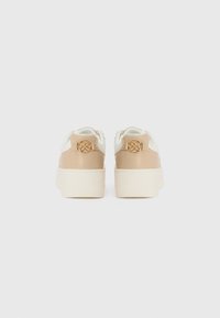 Sneakers med en beige, glat syntetisk overdel, hvide detaljer og en struktureret platformssål. Bemærkelsesværdigt guldfarvet hardware på hælen.