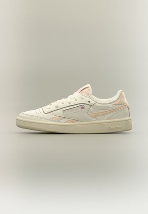 Κρεμ και ανοιχτό ροζ χαμηλό Reebok sneaker με κορδόνια, υφή στην σόλα και λογότυπο Union Jack στο πλάι, σε απλό φόντο.