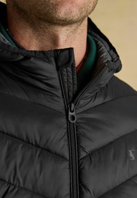 Čierna prešívaná bunda s vysokým golierom, horizontálnym prešívaním a zipsom vpredu. Nylonový materiál s hladkou textúrou a minimalistikou akcentmi.