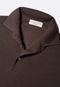 Polo marrone realizzato in tessuto testurizzato, con colletto strutturato, due bottoni e un'etichetta con scritto "Filippo De Laurentiis royal merino."