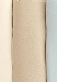 Drie rollen stof in zachte kleuren: crème, beige en lichtblauw, zij aan zij gepresenteerd, die hun textuur en kleurnuances laten zien.