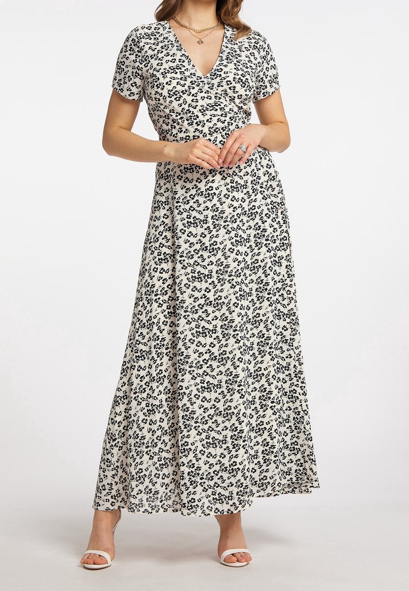 Maxikleid aus leichtem Stoff mit V-Ausschnitt, kurzen Ärmeln und einem schwarzen Leopardenmuster auf cremefarbenem Hintergrund. Hat eine fließende Silhouette.
