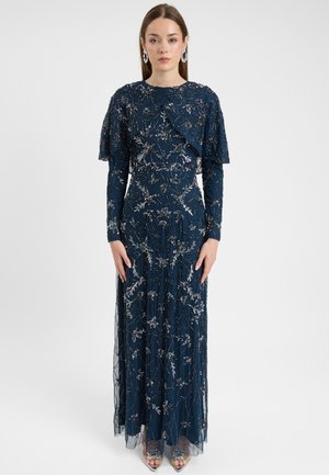 Navy blauwe lange jurk met ingewikkelde zilveren bloemenborduursels, lange mouwen, gerimpelde schouderdetails en een vloeiende rok.