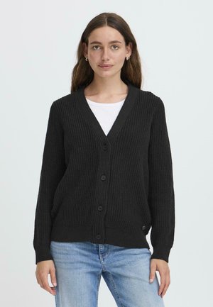 Svart ribbestrikket cardigan med V-hals, med seks knapper og lange ermer. Stylet over en hvit skjorte, myk tekstur og avslappet passform.