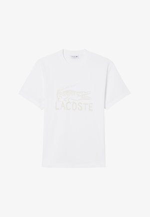 T-shirt bianca a maniche corte con scollo rotondo, logo coccodrillo Lacoste in rilievo e scritta "LACOSTE" al centro davanti.