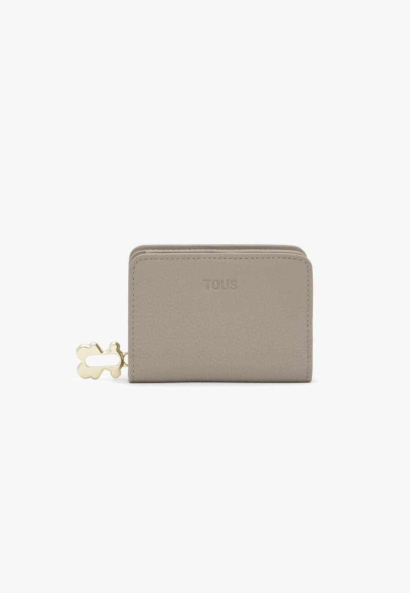 Cartera de cuero beige con acabado texturizado, que presenta un tirador de cremallera con forma de oso en tono dorado y el logo "TOUS" en relieve.