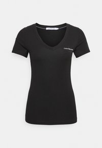 Svart kortärmad t-shirt med v-ringning. Har Calvin Klein Jeans-logotypen i vitt på vänster bröst. Slätt bomullstyg.