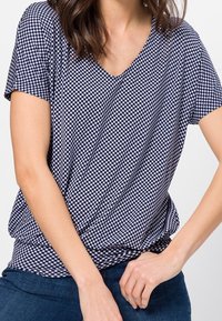 Tričko s námořnicko-bílou kostkovanou tkaninou V-výstřihem a krátkými rukávy, vyrobené z měkké, lehké látky. Má volnější střih.