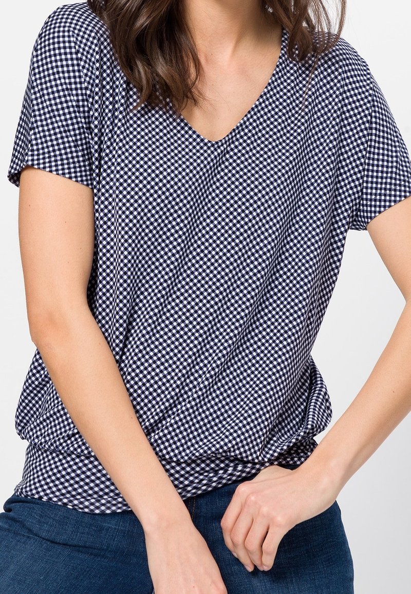 Tričko s námořnicko-bílou kostkovanou tkaninou V-výstřihem a krátkými rukávy, vyrobené z měkké, lehké látky. Má volnější střih.