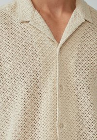 Gebreide shirt in off-white, met een ruitpatroon, korte kraag en knoopsluiting. Gestructureerde stof met een lichte uitstraling.