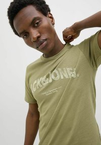 Groene katoenen T-shirt met een ronde hals, voorzien van een textuurlogo in lichte kleur en een relaxte pasvorm. Korte mouwen en een gladde textuur.