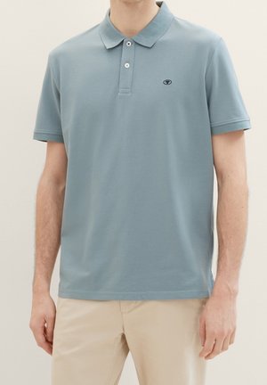 Polo bleu clair en mélange de coton, doté d'un col classique, d'une patte de boutonnage à trois boutons et d'un petit logo sur le côté gauche de la poitrine. Manches courtes.