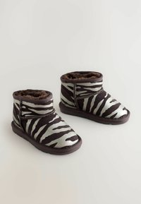 Stivali alla caviglia con motivo zebratore nero e argento, foderati in pelliccia sintetica, dotati di una fascia in Velcro e suole in gomma testurizzata.