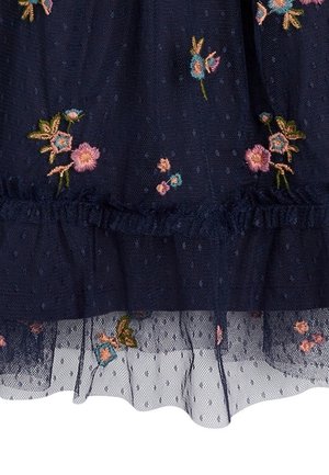 Tissu bleu foncé transparent à petits pois, avec des fleurs brodées roses et bleues aux tiges vertes et des détails froncés.
