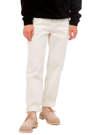Pantalones de mezclilla blanca con puños enrollados, combinados con botas de tobillo de color beige claro que tienen cordones y suelas texturizadas.