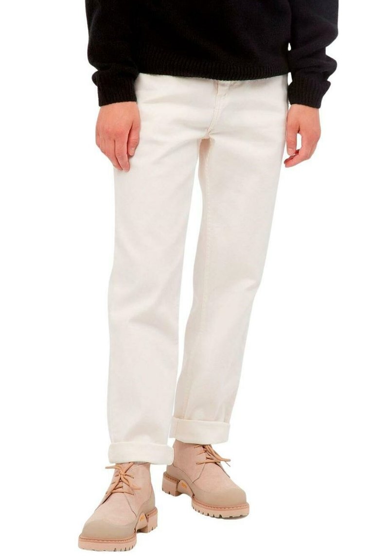 Pantalones de mezclilla blanca con puños enrollados, combinados con botas de tobillo de color beige claro que tienen cordones y suelas texturizadas.