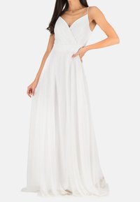 Bíl dress s dlouhým výstřihem, přiléhavým korzetem, V-výstřihem a tenkými ramínky. Volná sukně z lehké, průsvitné látky.