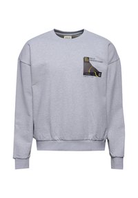 Grå bomullströja med långa ärmar, rundad halsringning och ribbade muddar. Har ett grafiskt tryck i svart och gult på framsidan.