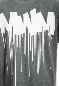 Camiseta gris con grandes letras blancas en estilo graffiti y gotas debajo del texto, hecha de un tejido suave y texturizado.