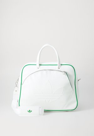 Bolsa deportiva rectangular blanca con ribetes verdes, bolsillo frontal con cremallera, asas superiores y correa de hombro ajustable con parche de logo.