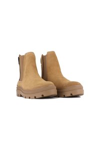 Botine scurte din suede bej, cu panouri elastice pe laterale, talpă din cauciuc robustă și cusături decorative. Au vârful rotunjit și suprafețe exterioare texturate.