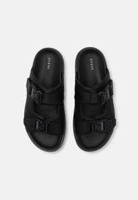 Infradito neri con fasce testurizzate, fibbie regolabili e suola imbottita. Presentano il marchio "GUESS" sul plantare e sulle fasce.