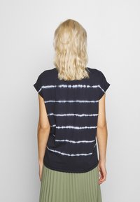 Černé tričko s tie-dye vzorem a vodorovnými bílými pruhy. Krátké rukávy a volný střih, vyrobené z měkké, prodyšné tkaniny.