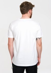 White cotton t-shirt with a round neckline and short sleeves. The back is plain, featuring a smooth texture and a relaxed fit.