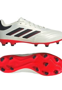 Botas de fútbol blancas con acentos negros y tres rayas negras, con una suela roja y tachuelas negras. Textura suave, diseño ligero.