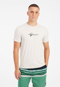 Lichtbeige korte mouw t-shirt van zachte stof, met een zwart grafisch logo op de borst. Gecombineerd met groene gestreepte zwembroek.