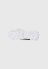 Sålen til en hvit sneakers viser et teksturert gummigrep med sirkulære og ovale former på en enkel hvit bakgrunn.
