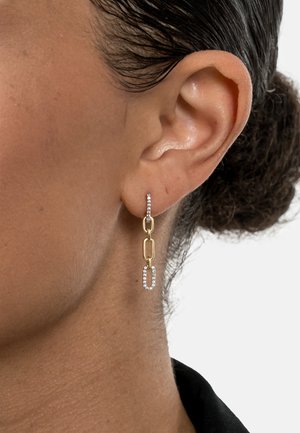 Ohrringe aus goldfarbenem Metall mit einem verbundenen Kettendesign und einem klaren Strassakzent. Glatte Textur mit einer modernen, geometrischen Form.