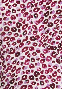 Tissu blanc avec des taches imprimées léopard en violet et bordeaux, présentant différentes tailles et formes. Texture douce, matériau léger.